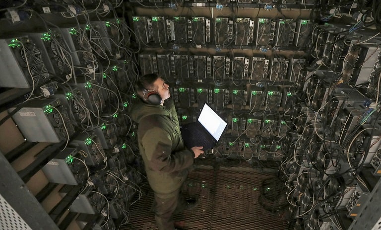 مزرعه ماینینگ ارز دیجیتال در ایران، با اپراتور در حال نظارت بر دستگاه‌های استخراج.